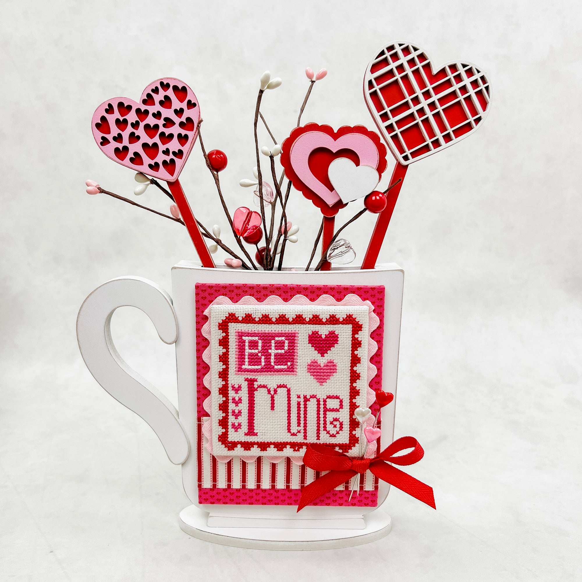 Valentine mug wood cross stitch display with red hearts on sticks. For displaying finished cross stitch pieces.