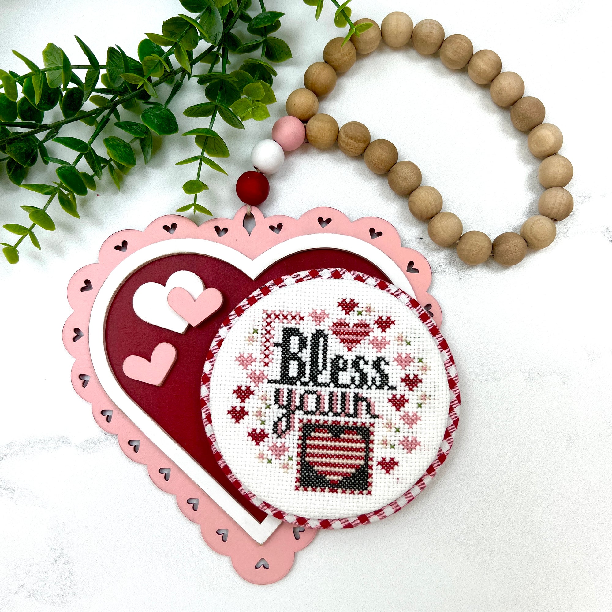 wood beaded garland shaped like a heart for displaying finished cross stitch pieces
