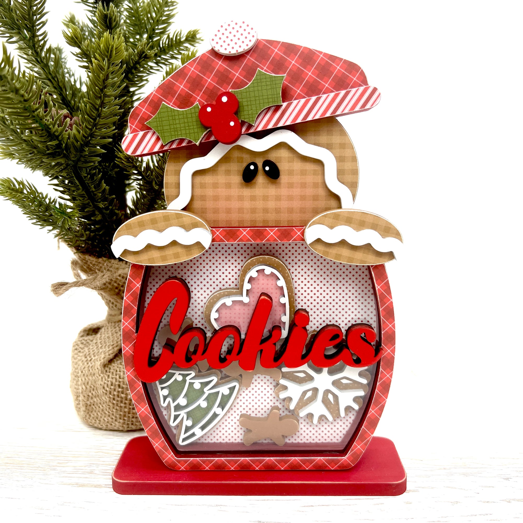 Gingerbread wood decor with a gingerbread man popping out of a cookie jar with a clear front and christmas cookies inside.