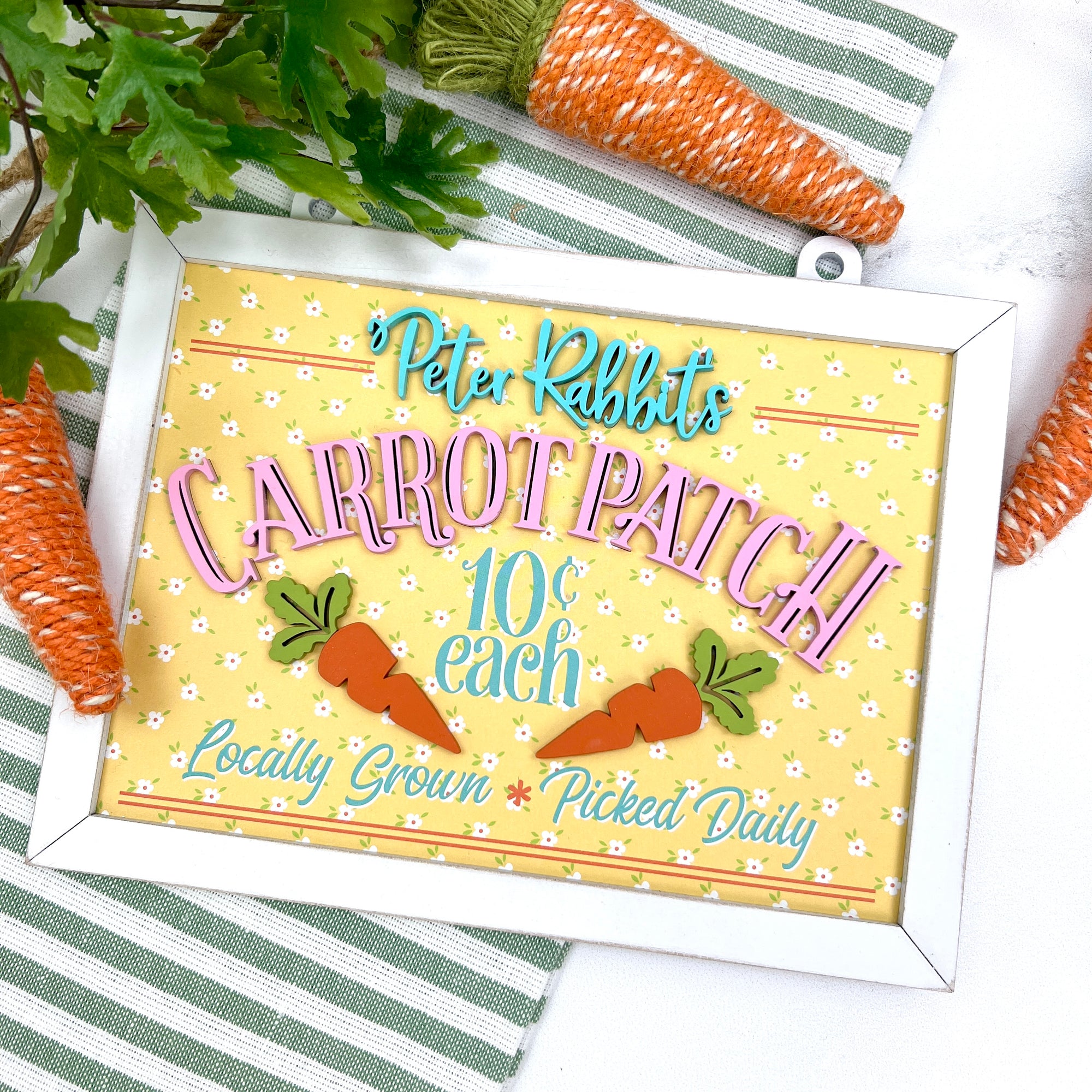 Pink, yellow, and teal Easter wood decor sign that says Peter Rabbits carrot patch