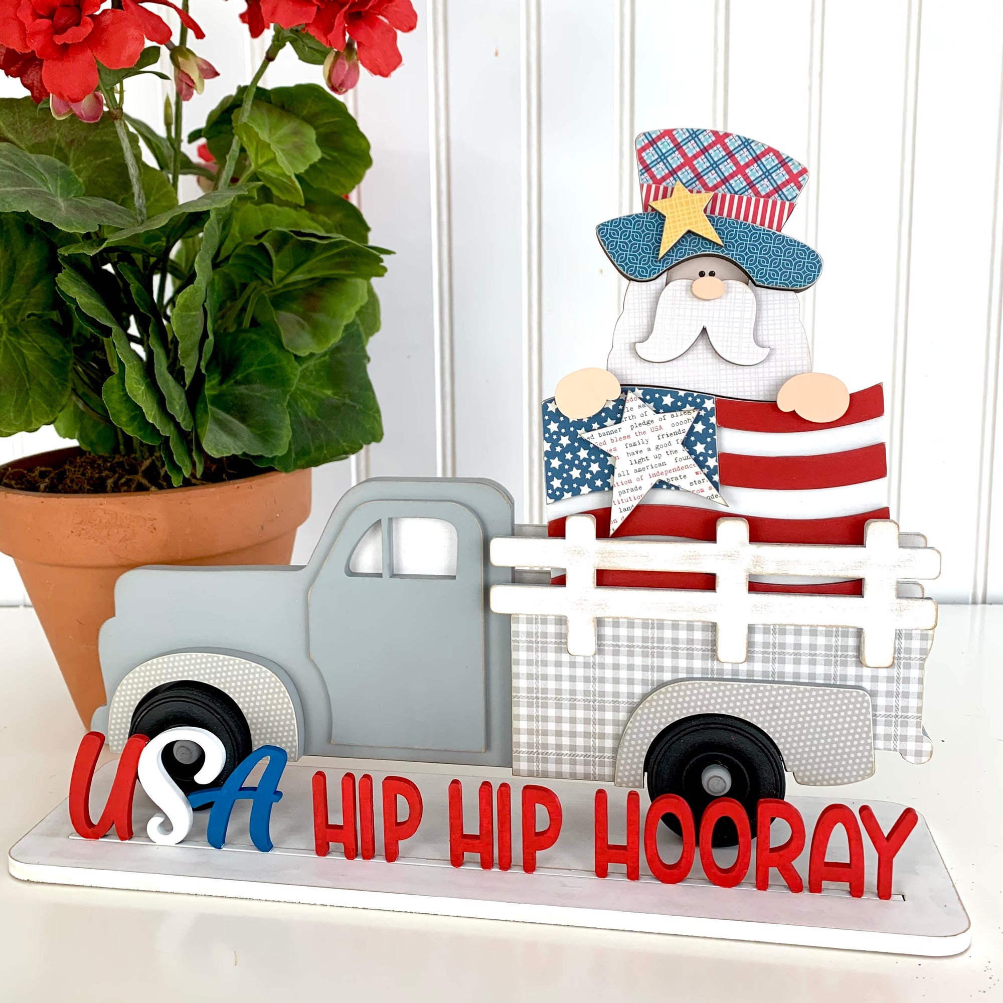 Pick up truck with seasonal 4th of July insert.  Uncle Sam holding a flag in the back of a pick up truck with a phrase that says USA Hip Hip Hooray.