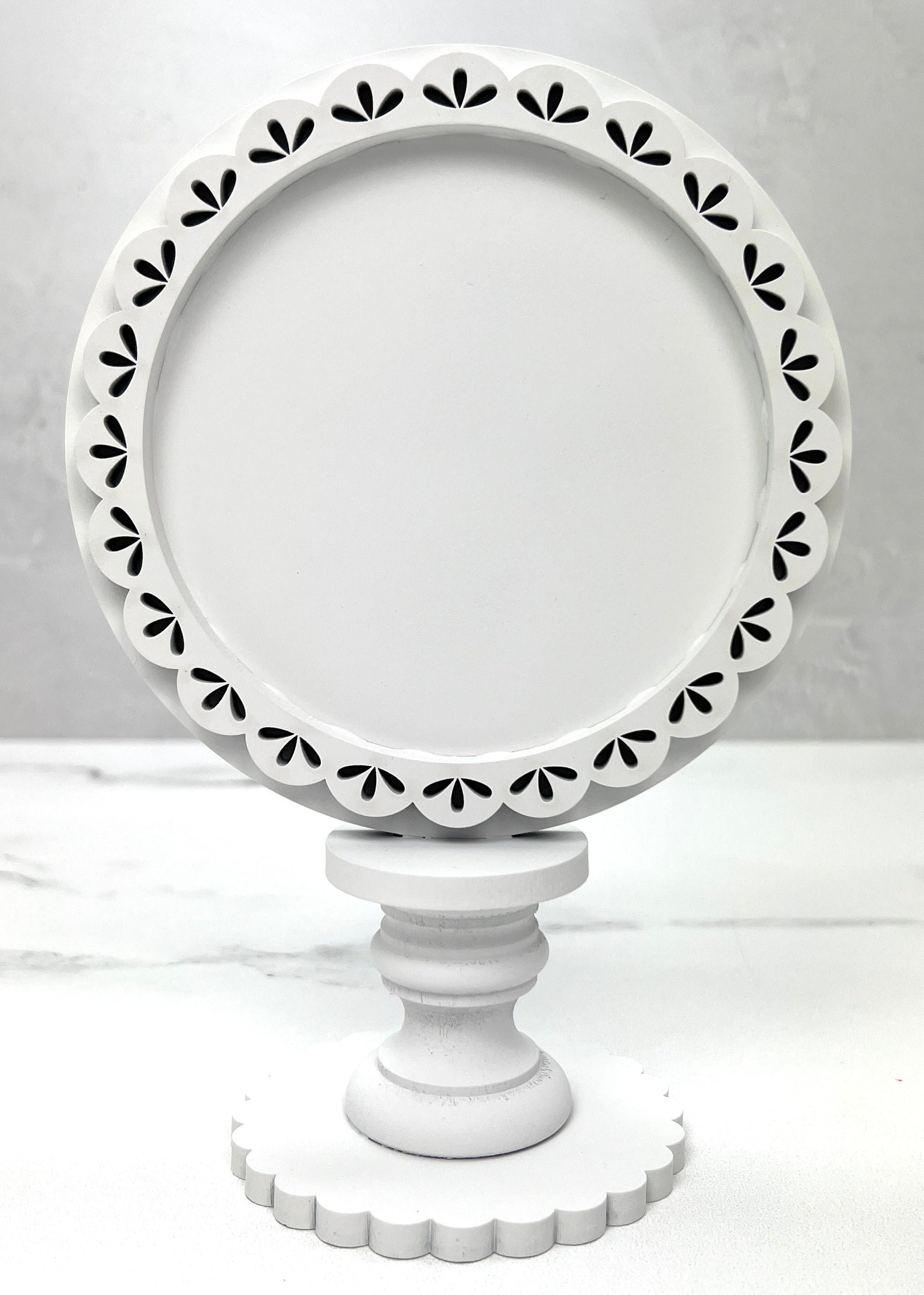 Round decorative frame on a pedestal for displaying finished cross stitch pieces. 